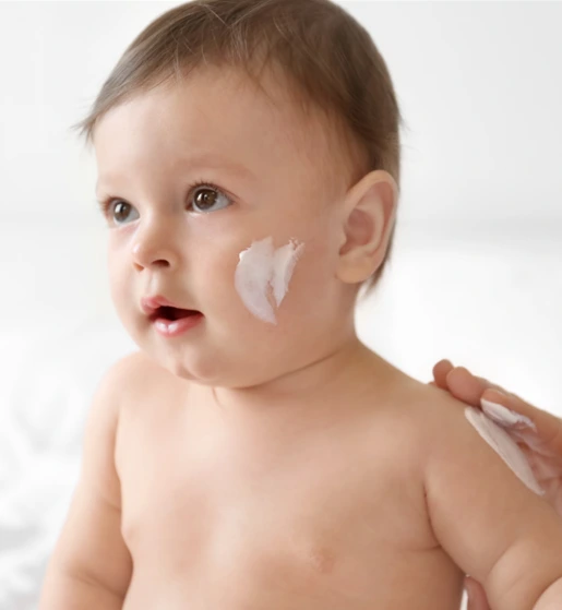 Baby with skincare cream applied on cheek